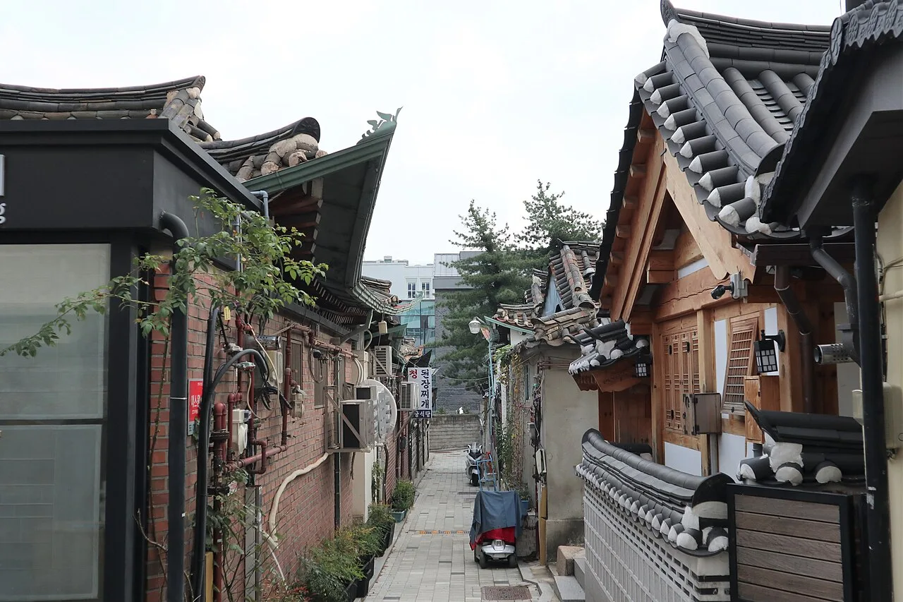 Visitors walking along a hanok-lined street in Bukchon Hanok Village on an autumn day