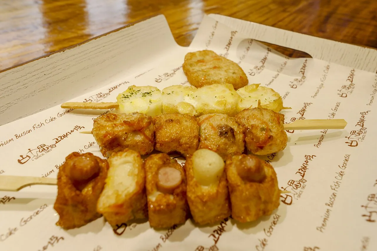 Fried Busan fish cake skewers in different shapes on branded paper