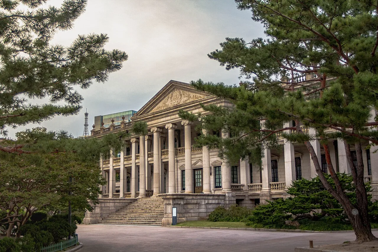 The neoclassical stone Seokjojeon hall with columns at Deoksugung, framed by pine trees