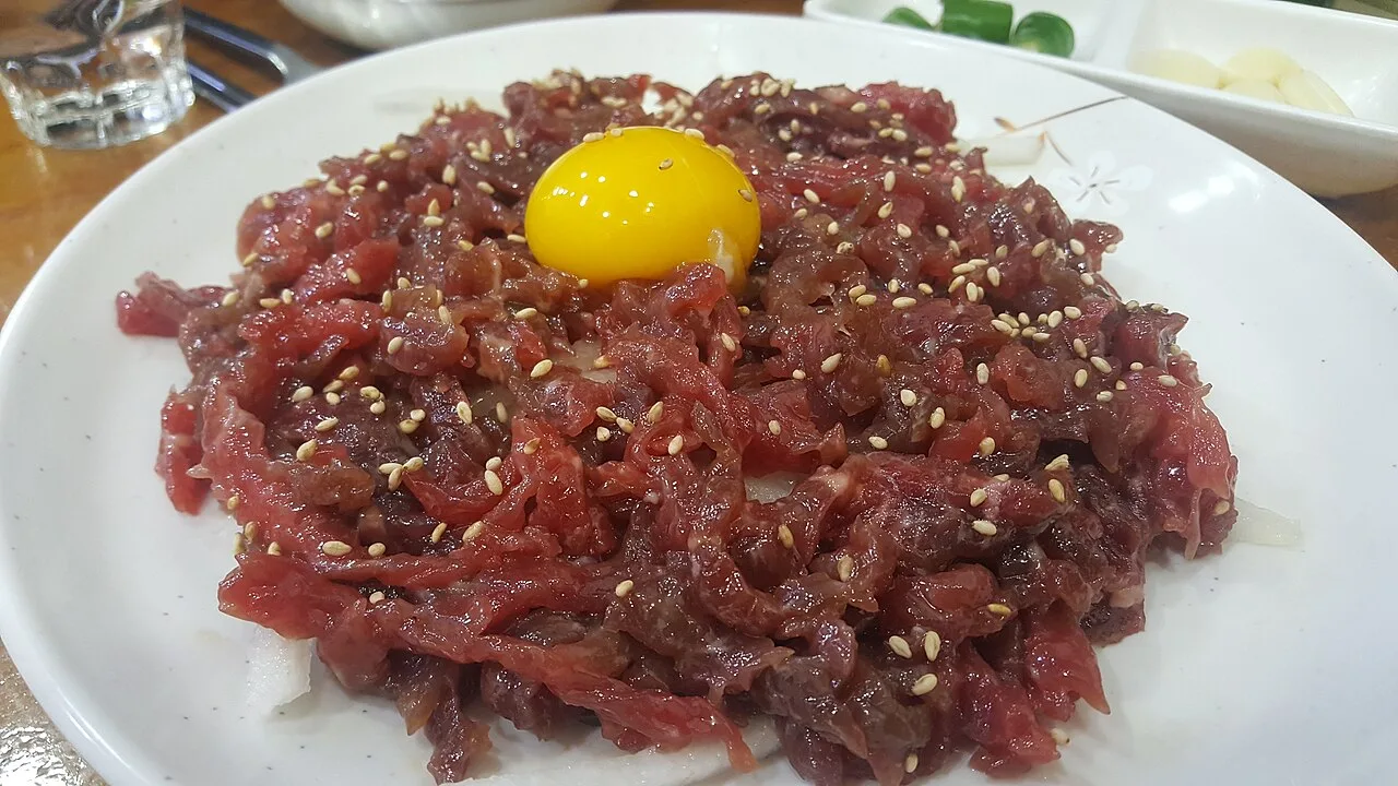 A plate of yukhoe, Korean raw beef, topped with an egg yolk and sesame seeds