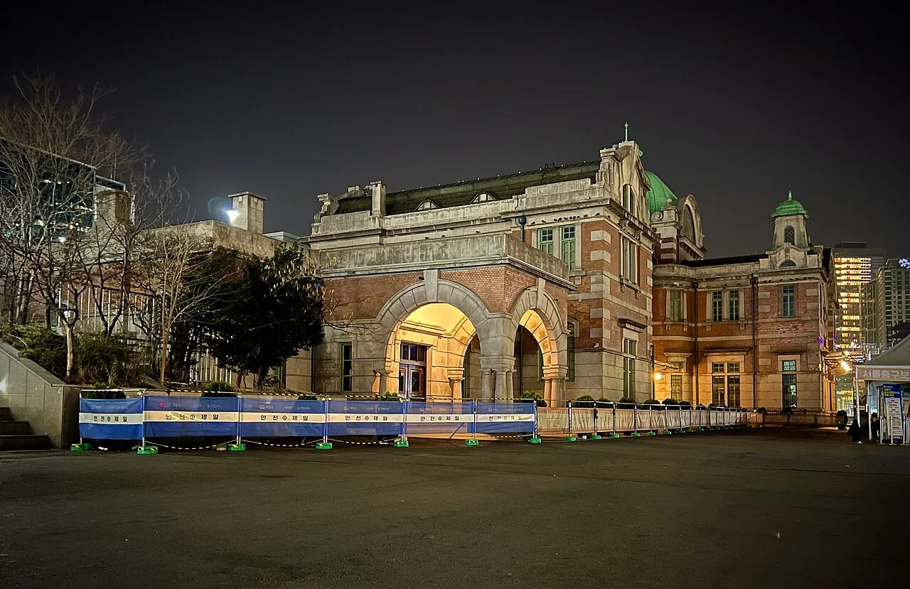 The old Seoul Station building at night with lit arches, seen from the station square