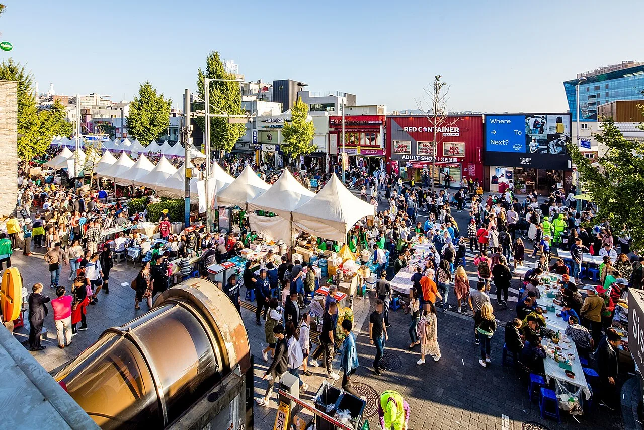 Crowds walking along Itaewon-ro during a street festival with food tents