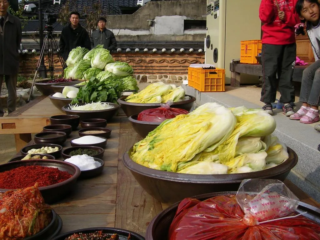 Bowls of chili paste, salted cabbage, radish and seasonings laid out in a hanok courtyard