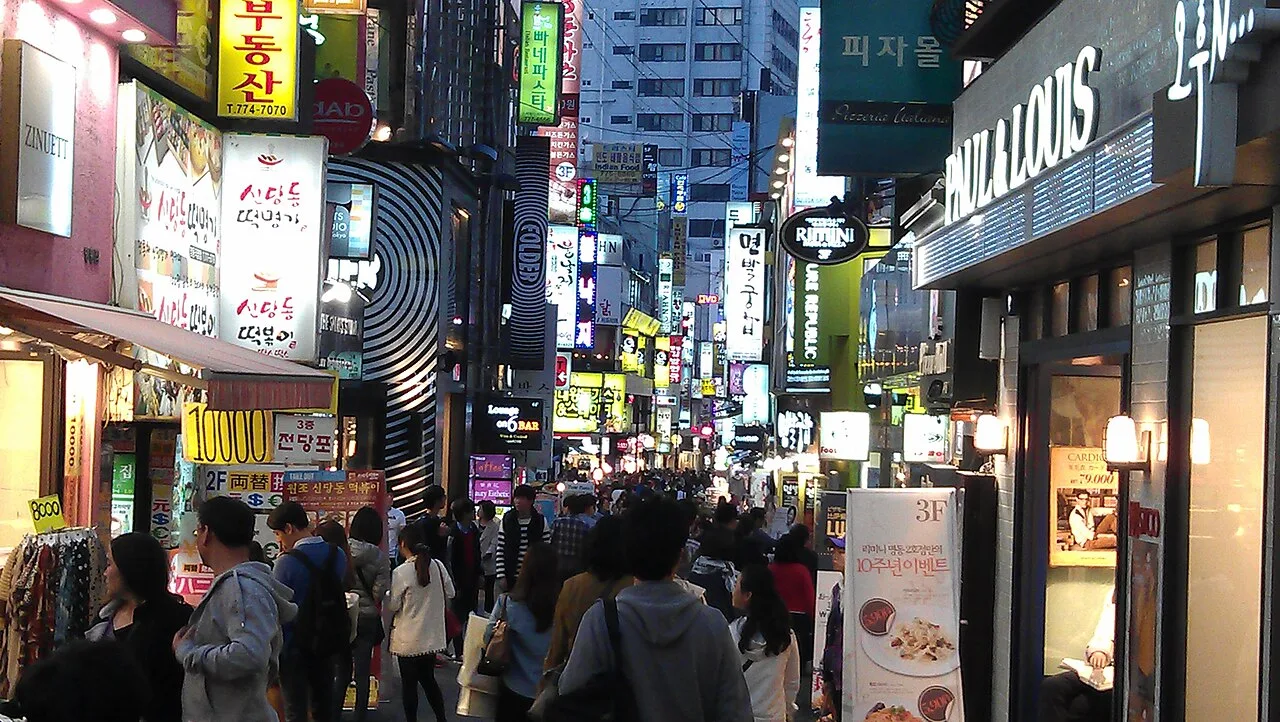 Myeongdong's main pedestrian street at night lined with brightly lit cosmetics shops