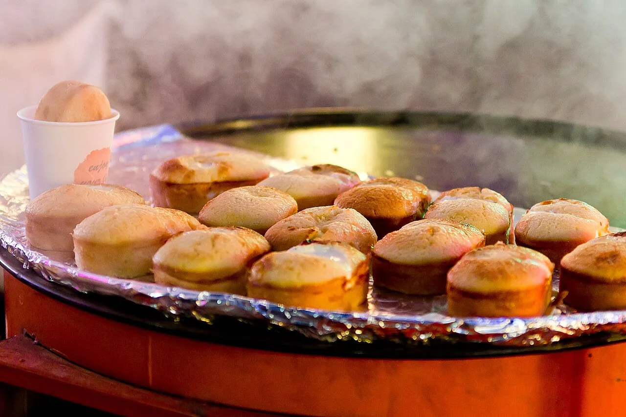 Rows of gyeranppang egg breads baking on a hot griddle at a street stall