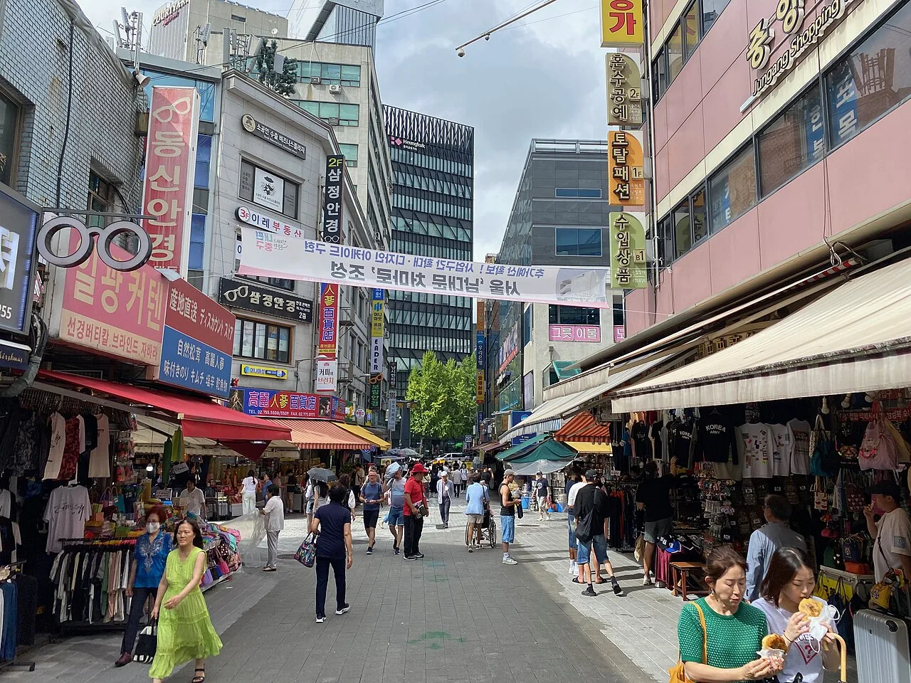 A Namdaemun Market shopping street lined with clothing and souvenir stalls under awnings