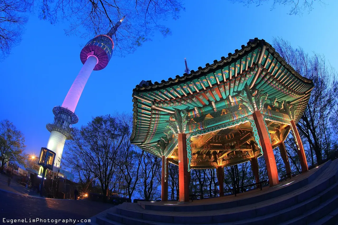 N Seoul Tower lit up at dusk next to the Palgakjeong pavilion on Namsan
