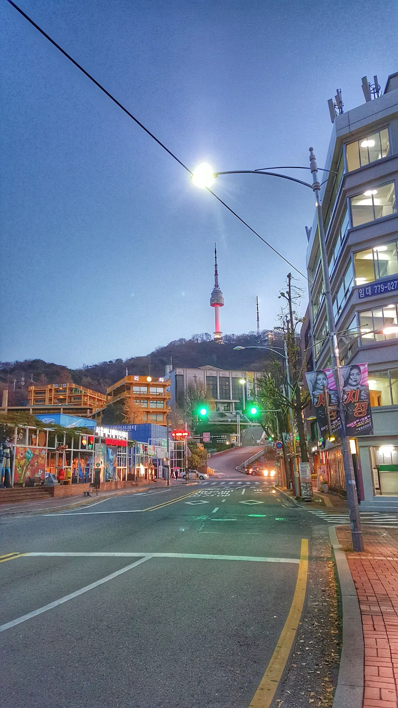 N Seoul Tower seen glowing above a quiet Seoul street at dusk