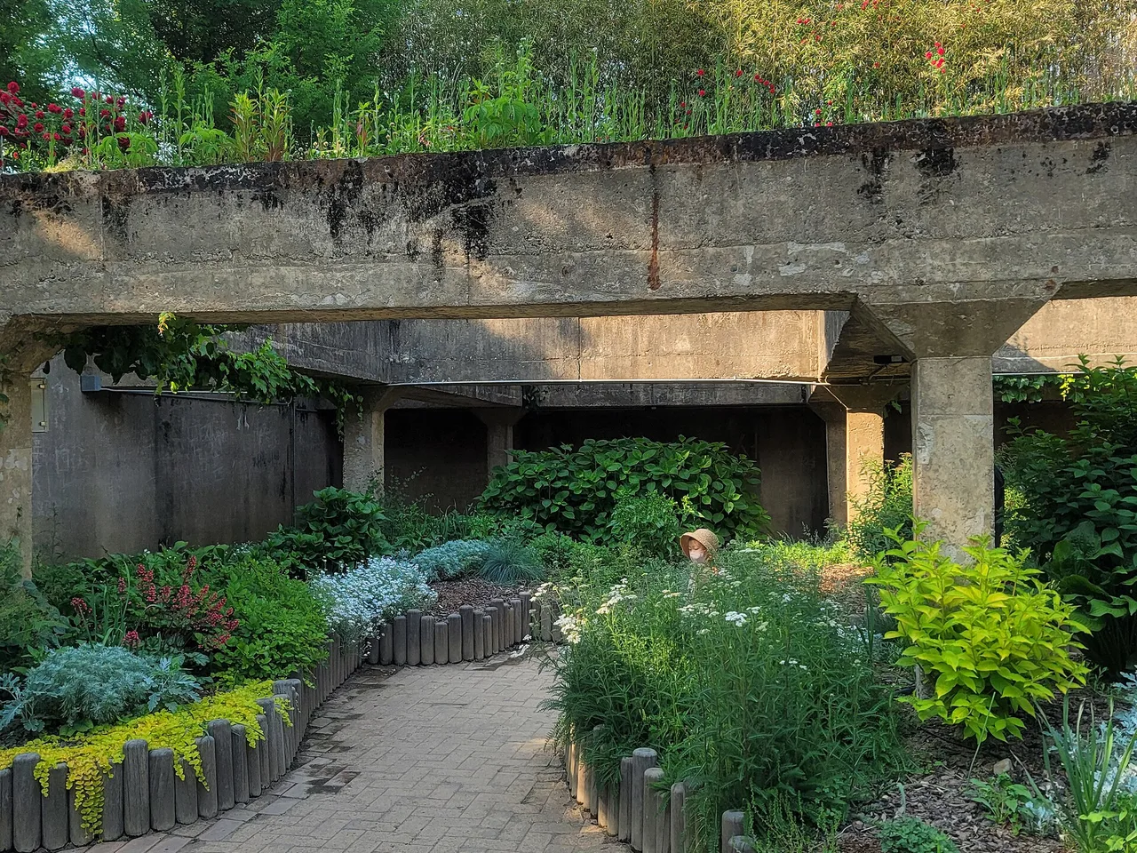 A garden path in Seoul Forest running under old concrete water-treatment structures covered with plants and flowers