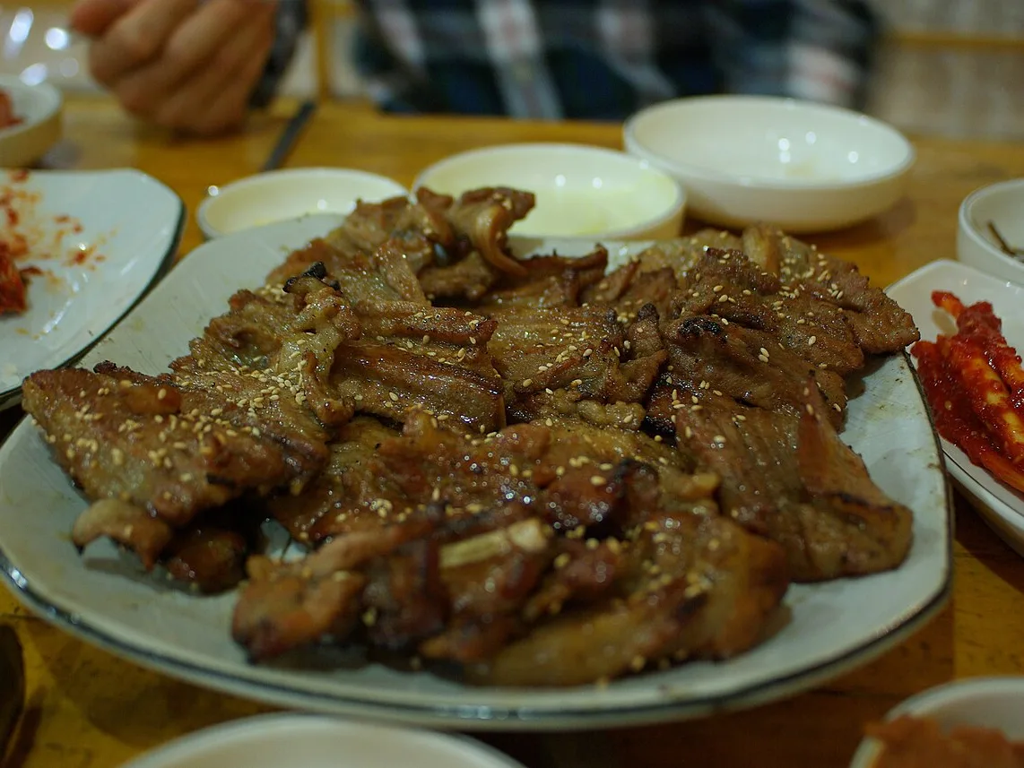 Plate of grilled marinated pork ribs with Korean side dishes