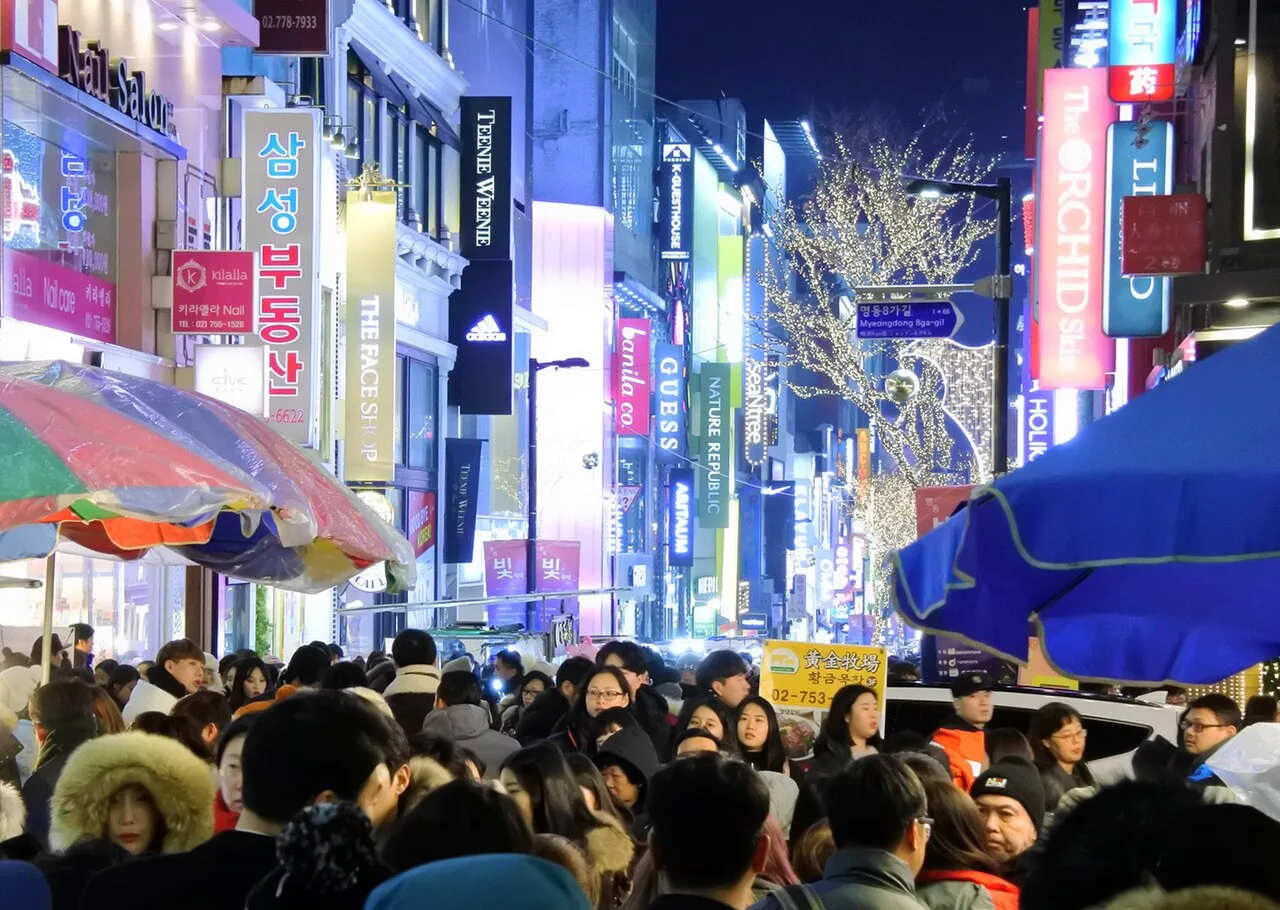 Crowds walking under Christmas lights and neon signs in Myeongdong on Christmas Eve