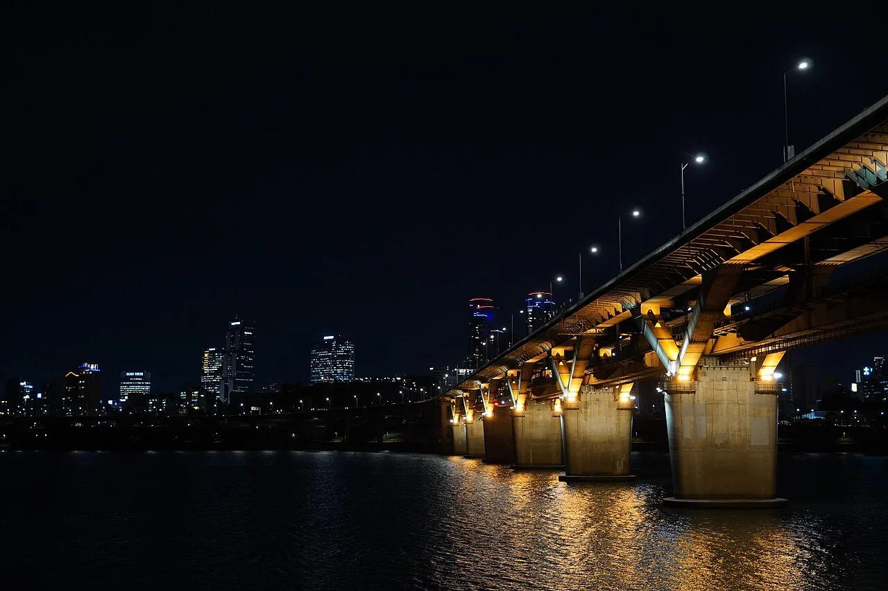Night view of a lit Han River bridge and the Seoul skyline reflected in the water at Ttukseom Hangang Park